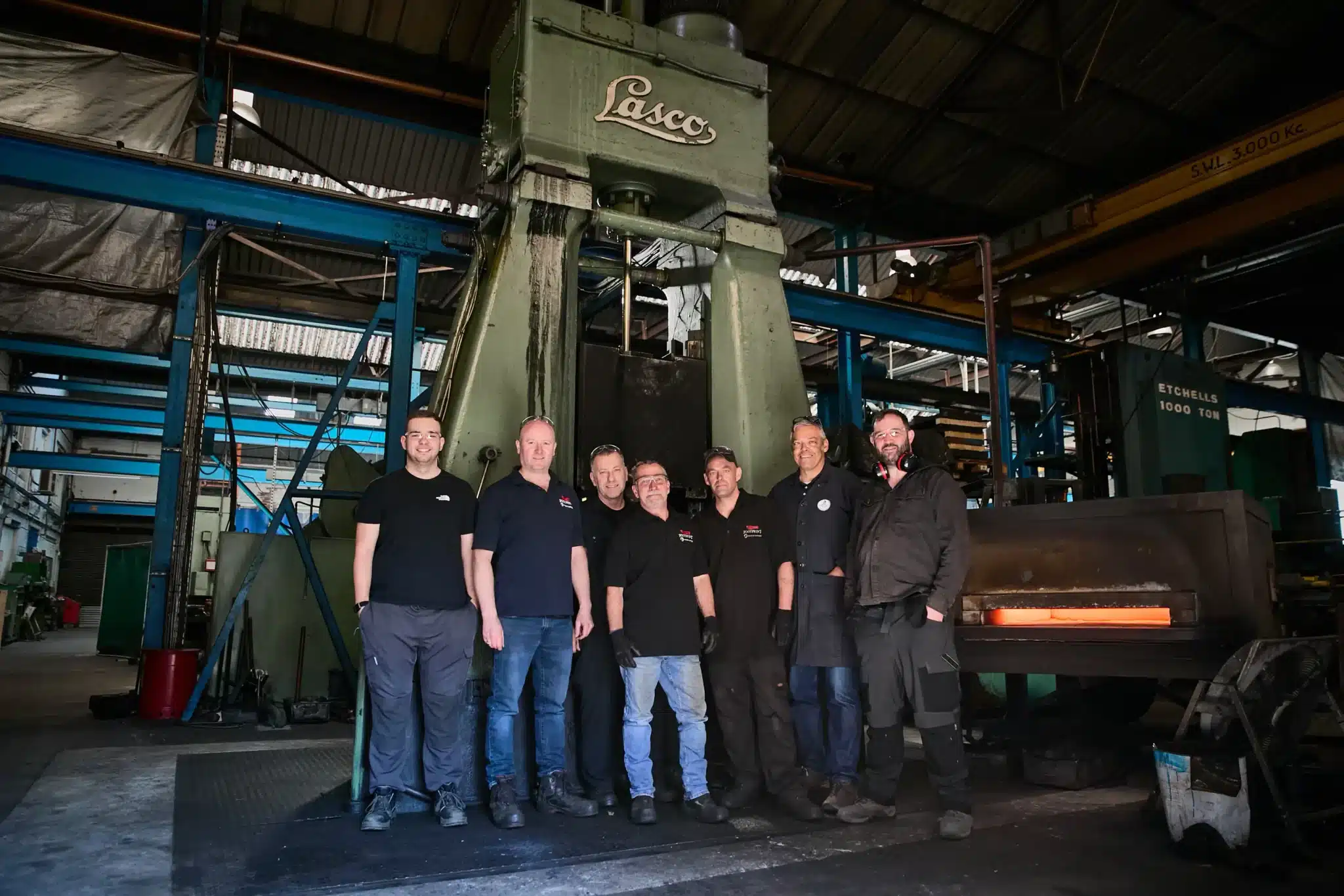 The Ernest Wright and Footprint Tools forging team standing before the green LASCO drop-forging hammer in Sheffield, where the Nurseryman Scissors are hot drop forged.
