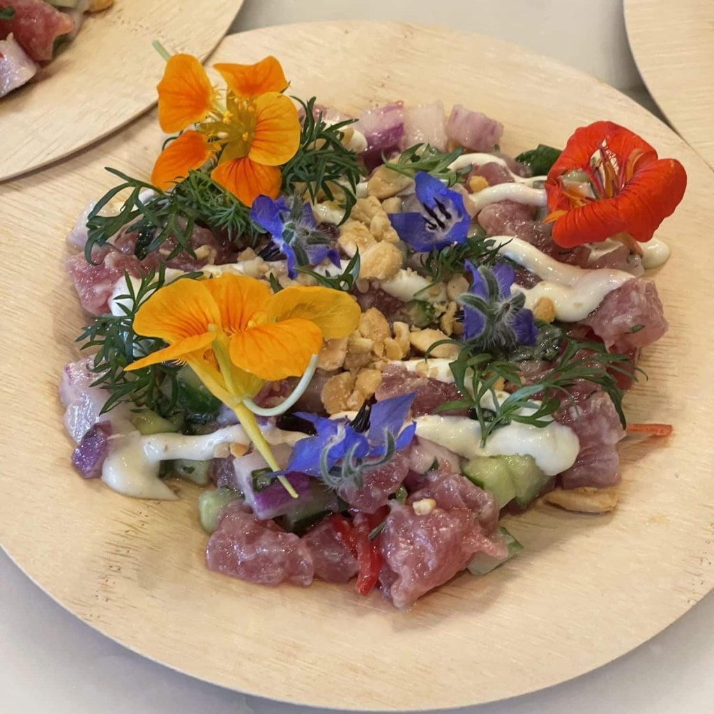 A course of raw tuna with cucumber, crushed nuts and a white dressing, scattered with nasturtium and borage flowers